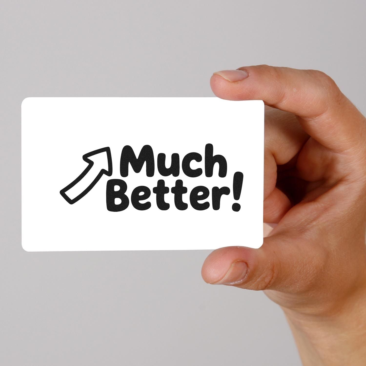 Hand holding a custom rubber stamp design reading "Much Better!" with arrow icon, ideal for motivational office stamping.