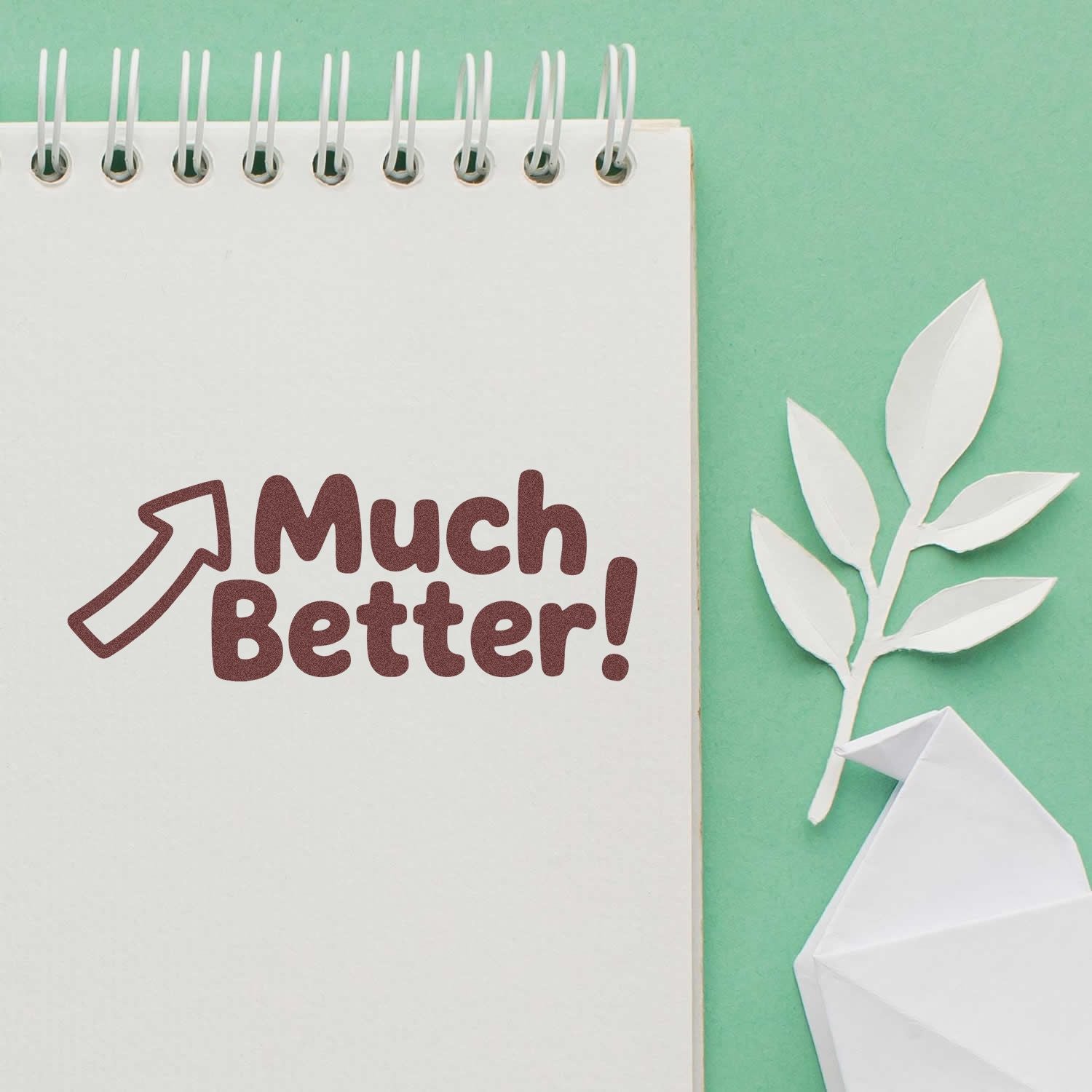 Much Better! arrow rubber stamp design on notebook, perfect for journaling, planners, and handmade paper crafts.