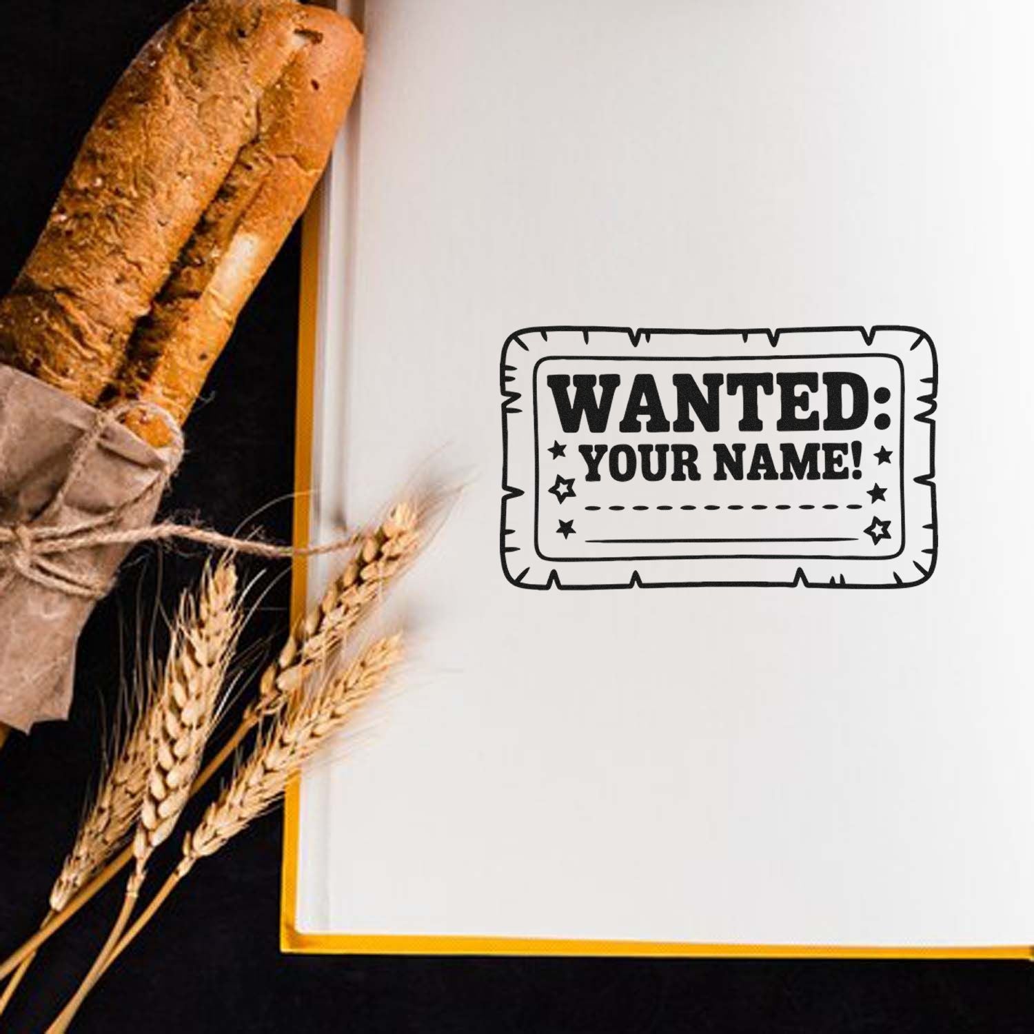 Personalized rubber stamp mockup with WANTED: YOUR NAME! design for bakery packaging and custom branding.
