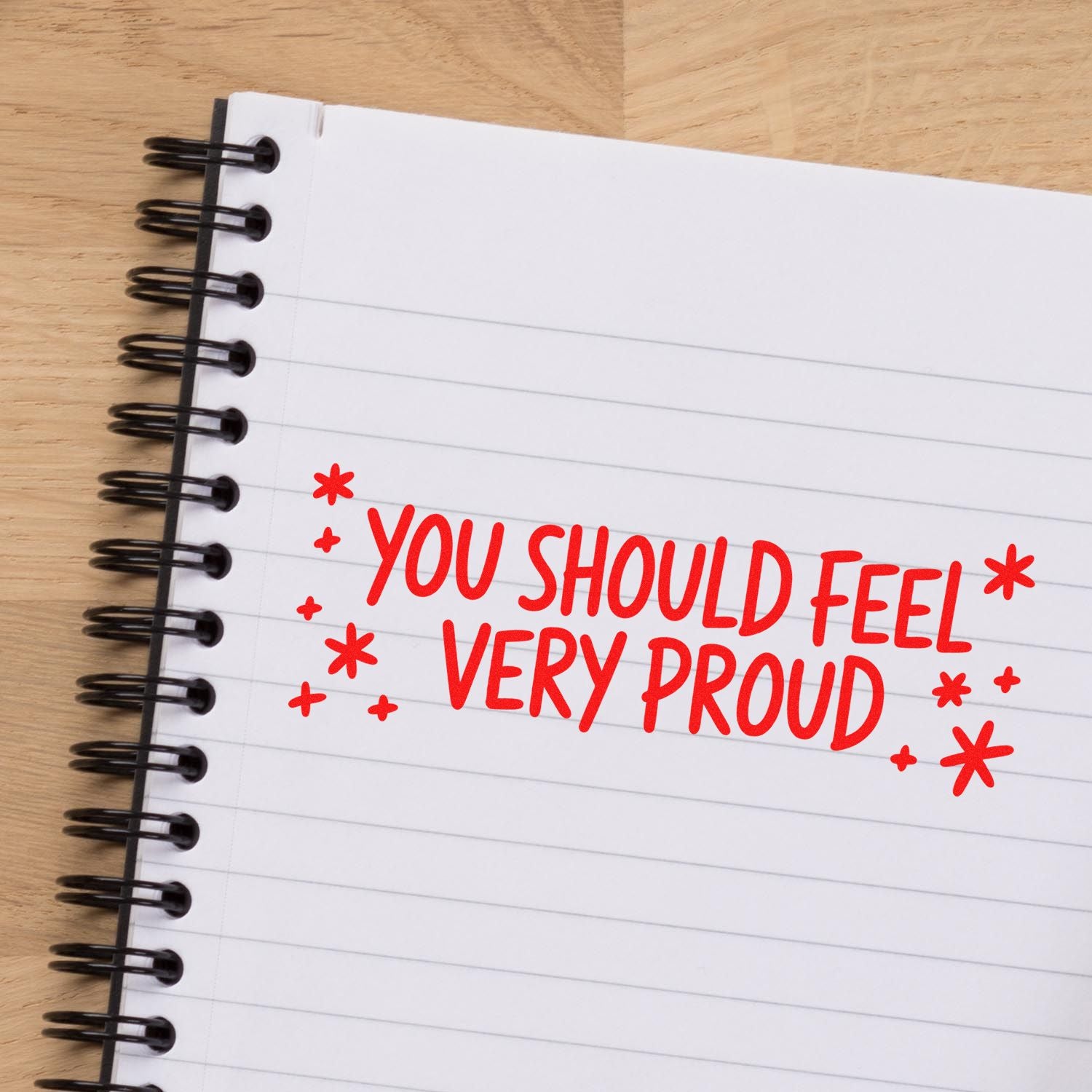 Red motivational rubber stamp reading You should feel very proud on notebook page for student encouragement.