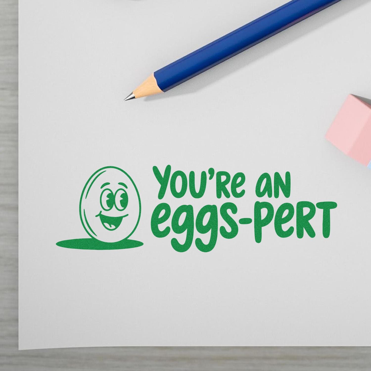 Funny rubber stamp reading "You're an eggs-pert" with smiling egg icon, ideal for Easter cards, teacher gifts, and office notes.