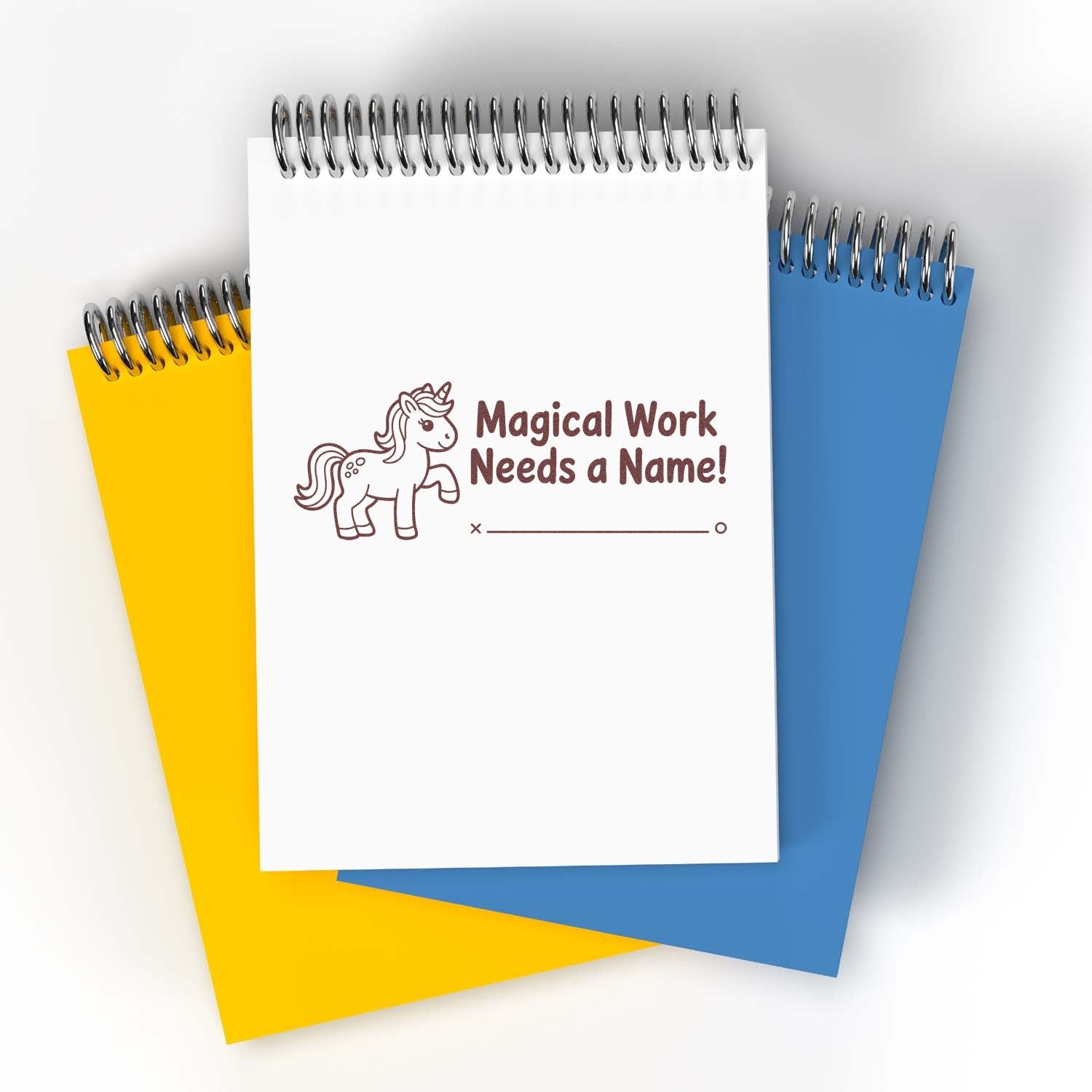 Custom unicorn rubber stamp mockup for personalized stationery, featuring Magical Work Needs a Name! on a spiral notebook.