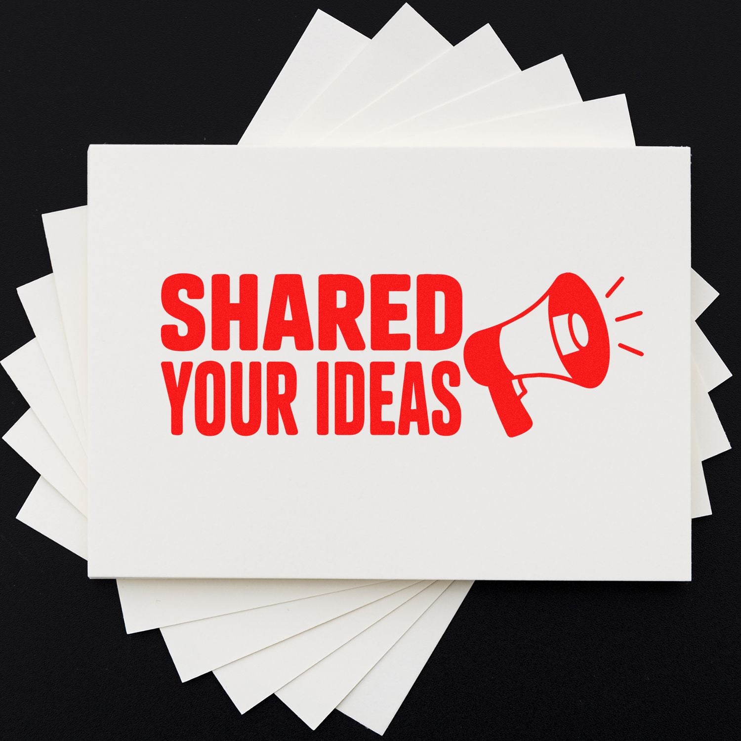 Custom rubber stamp with Shared Your Ideas text and megaphone design on stacked white cards.