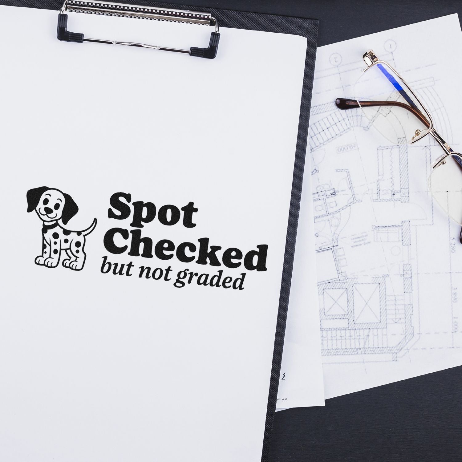 Custom rubber stamp reading Spot Checked but not graded with dog icon on clipboard beside eyeglasses and blueprints.