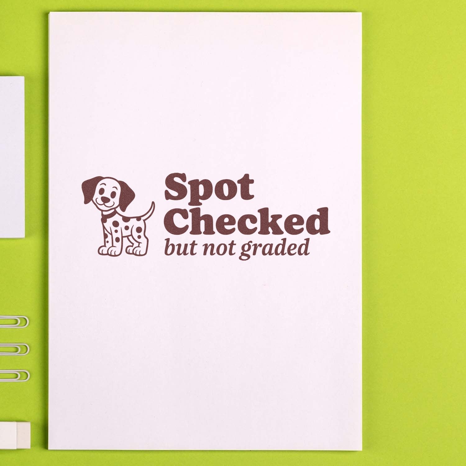 Rubber stamp impression reading Spot Checked but not graded with a dog icon on a notebook page.