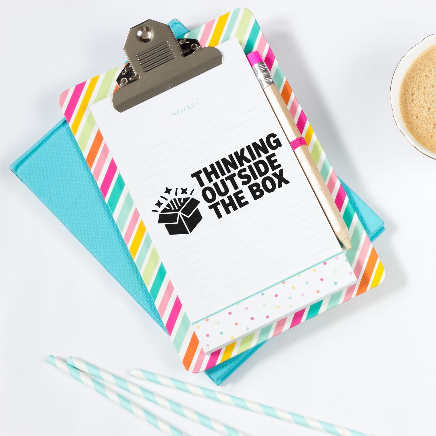 Rubber stamp on notebook reading Thinking Outside the Box with colorful clipboard, pencil and coffee.