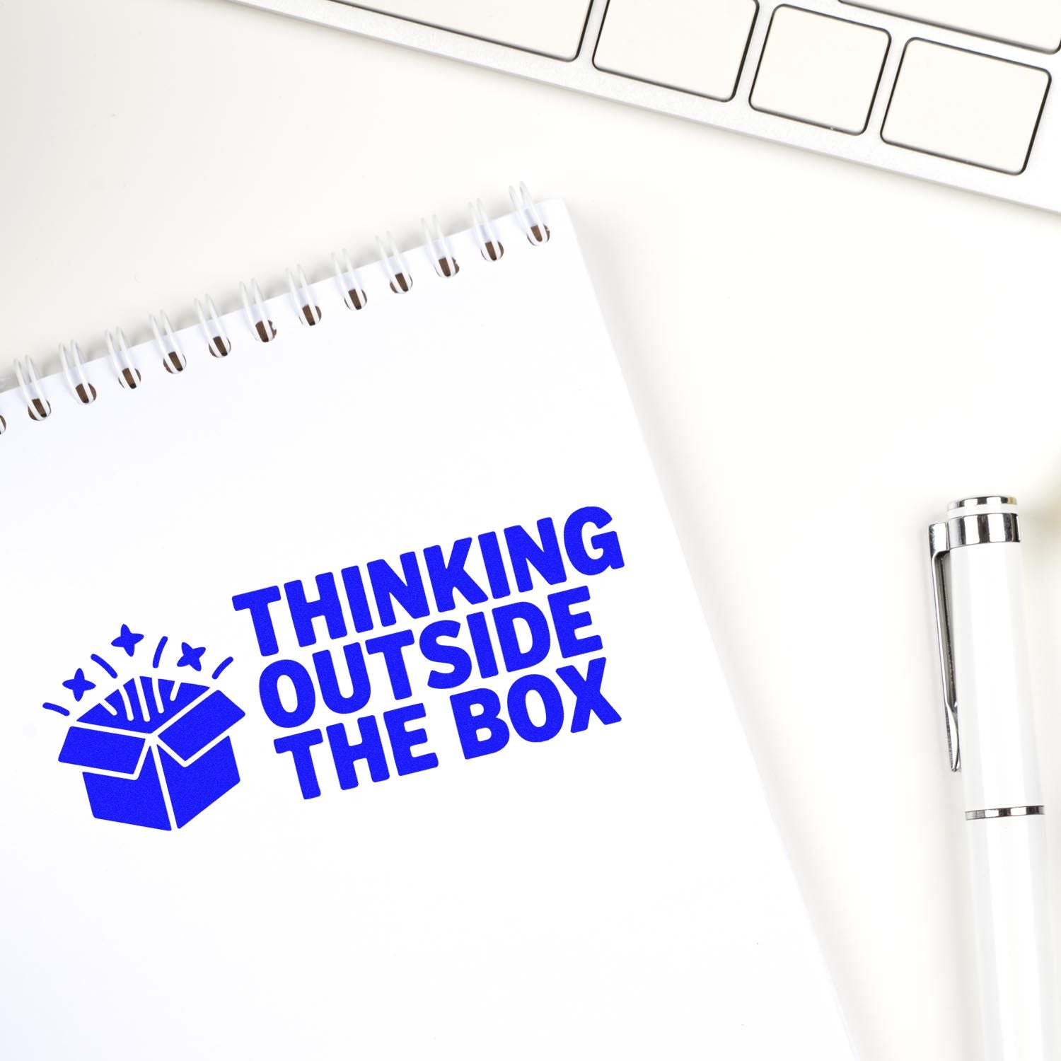 Blue custom rubber stamp reading Thinking Outside the Box on notebook, perfect for creative office branding and packaging.