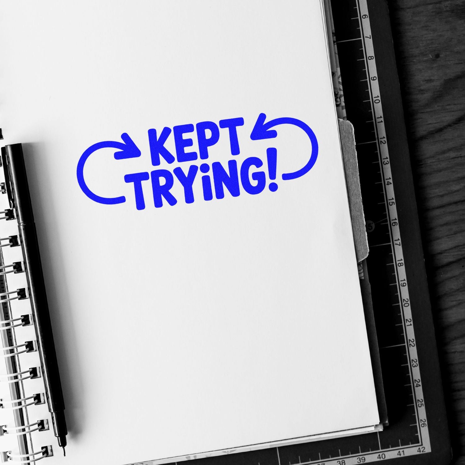 Bold Kept Trying rubber stamp design in blue on notebook page for motivational crafting and office projects.