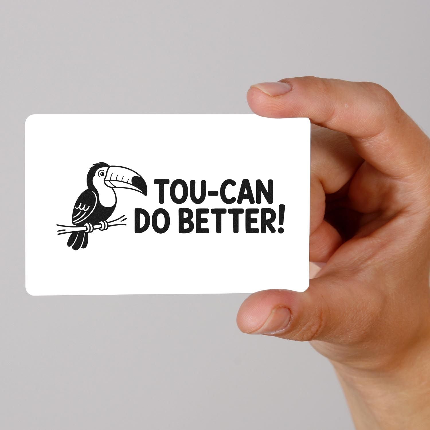 Humorous toucan do better rubber stamp design held in hand, featuring a toucan illustration and motivational pun text.