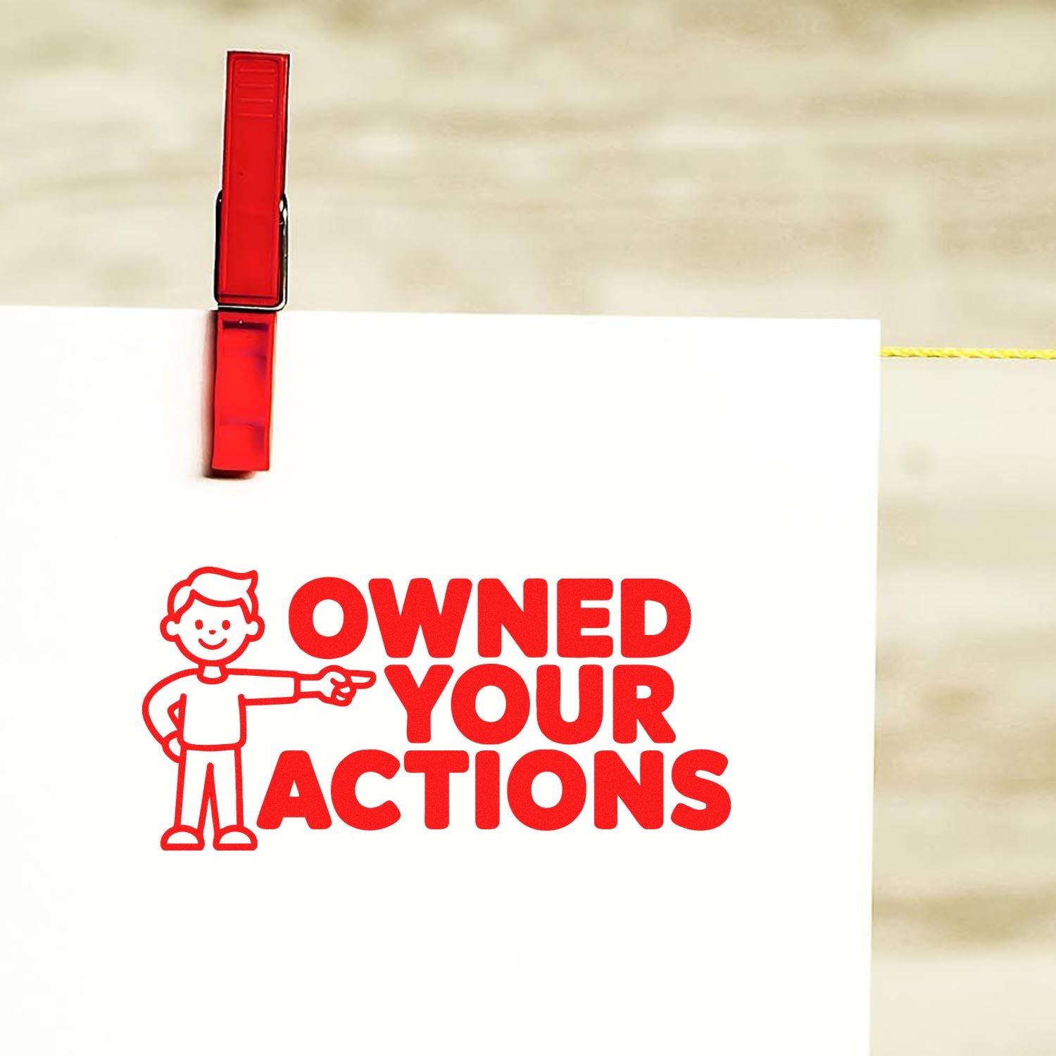 Red rubber stamp impression reading OWNED YOUR ACTIONS with cartoon figure, used for accountability and motivational messaging.