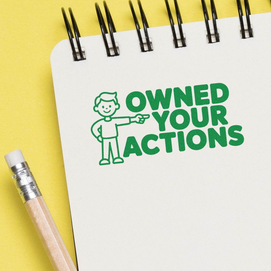 Rubber stamp with Own Your Actions message on notebook page, ideal for motivational classroom or office use.