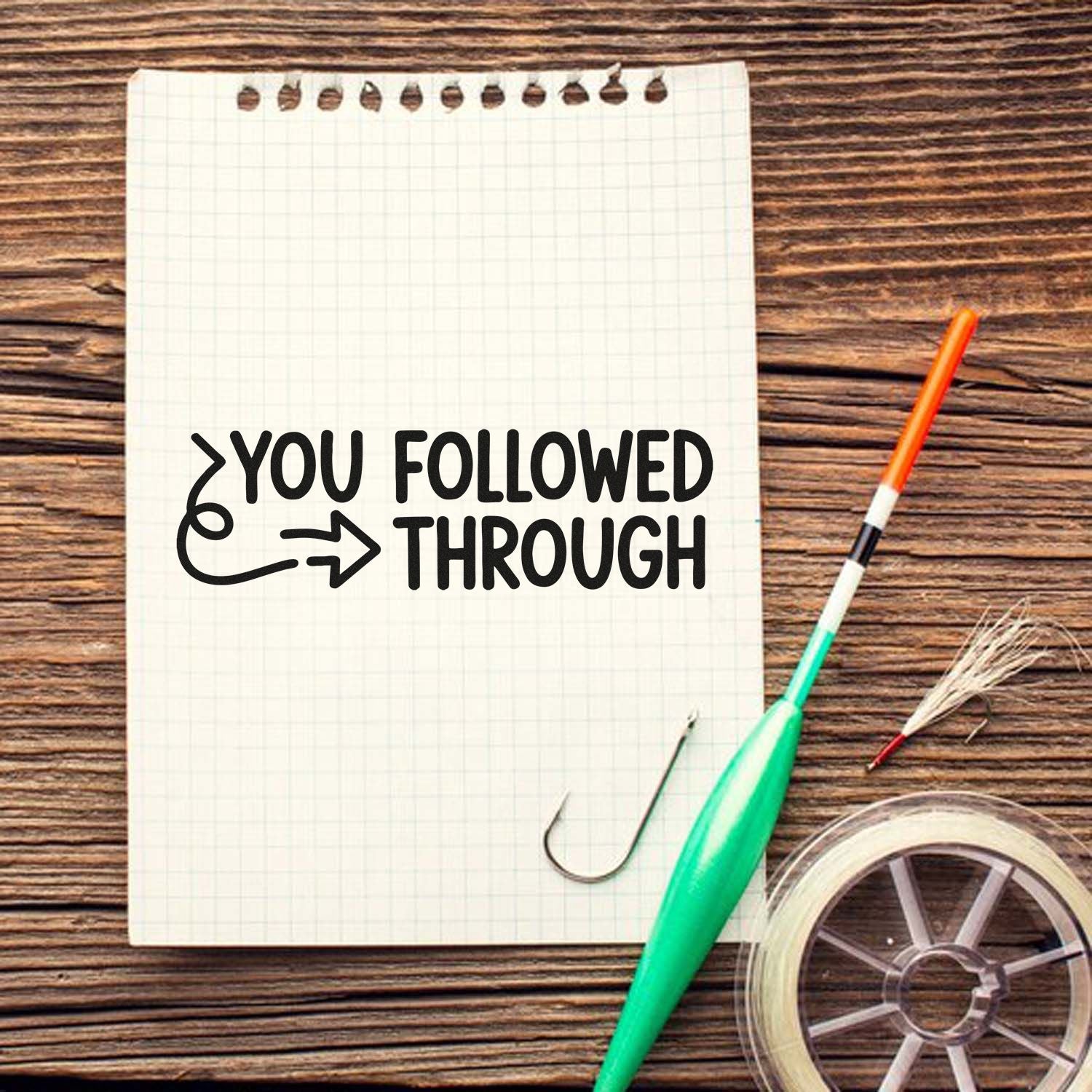 Custom rubber stamp design reading You Followed Through on notebook paper with craft tools and wood background.