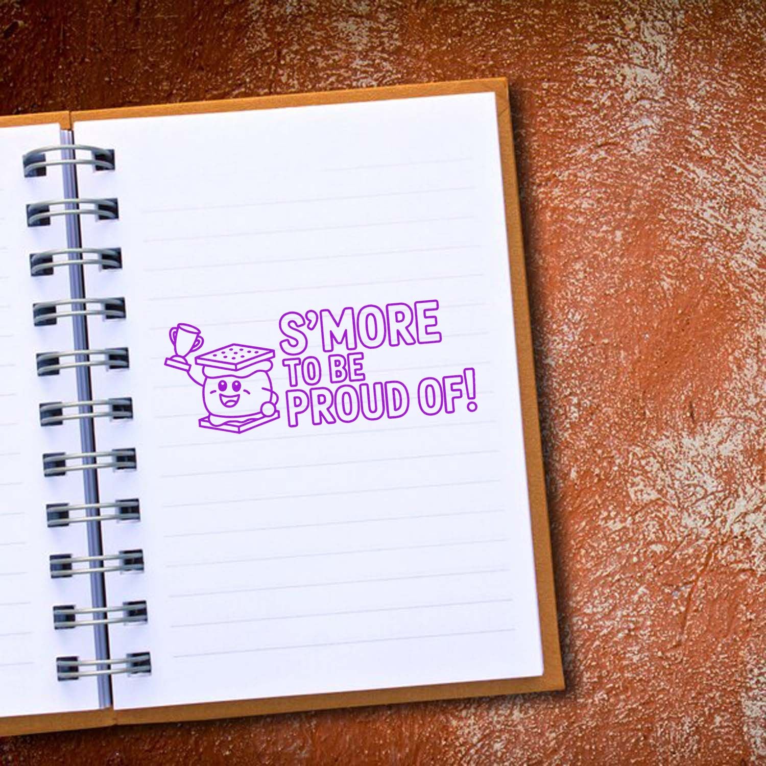 Motivational smore rubber stamp reading Smore to be proud of! on a lined notebook page.