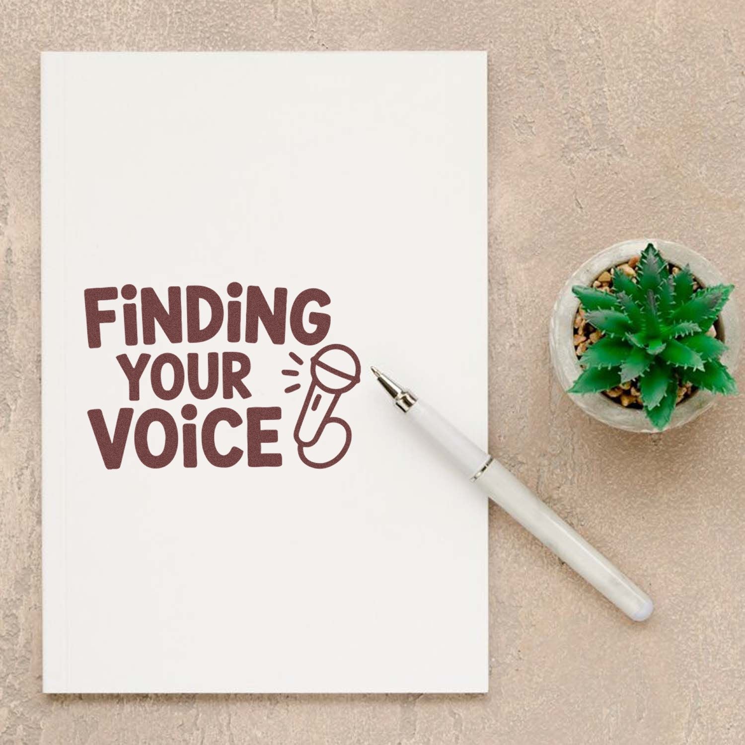 Rubber stamp design reading Finding Your Voice with microphone icon on notebook, ideal for creative journaling.