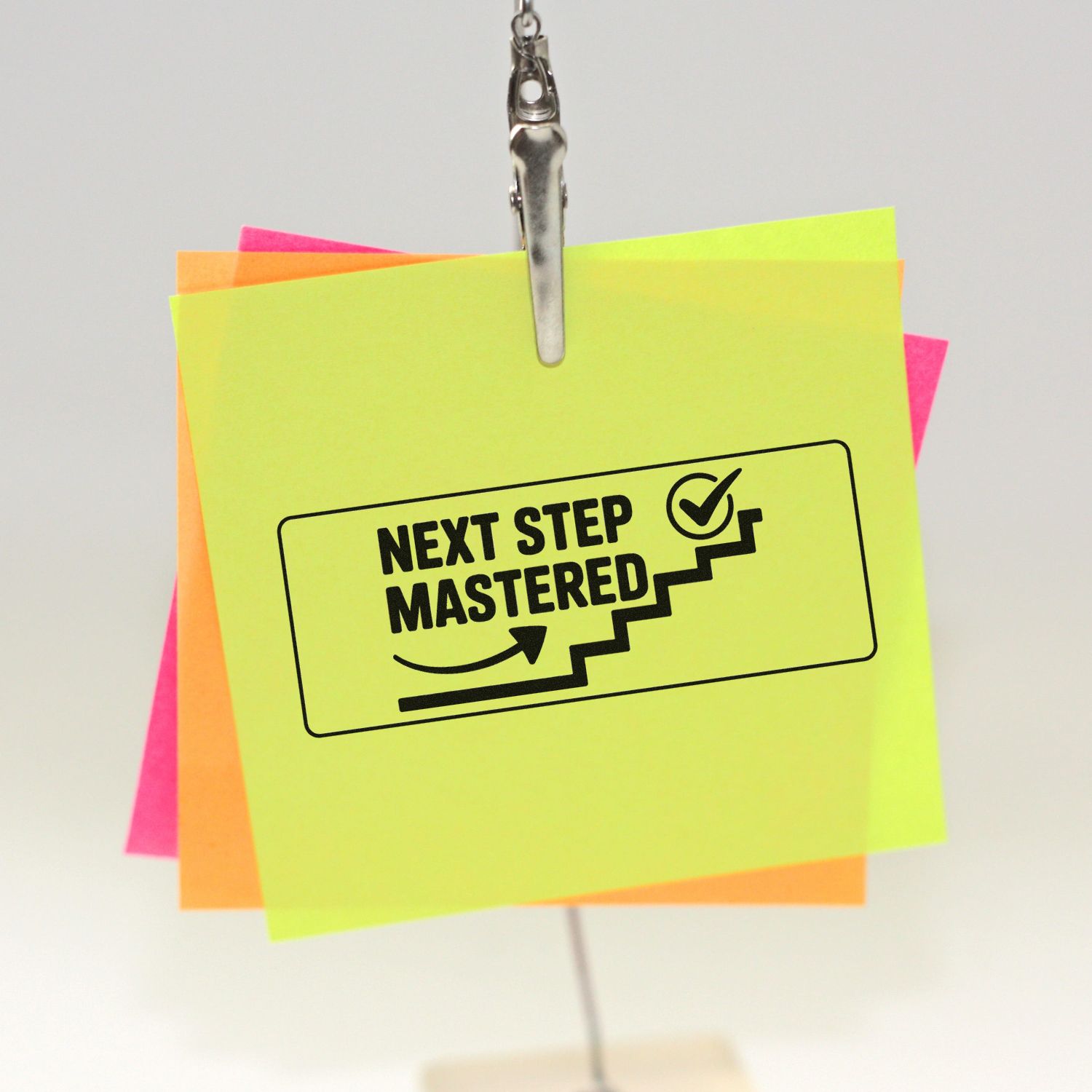Rubber stamp on sticky notes reading Next Step Mastered, a motivational office stamp for task completion and progress tracking.