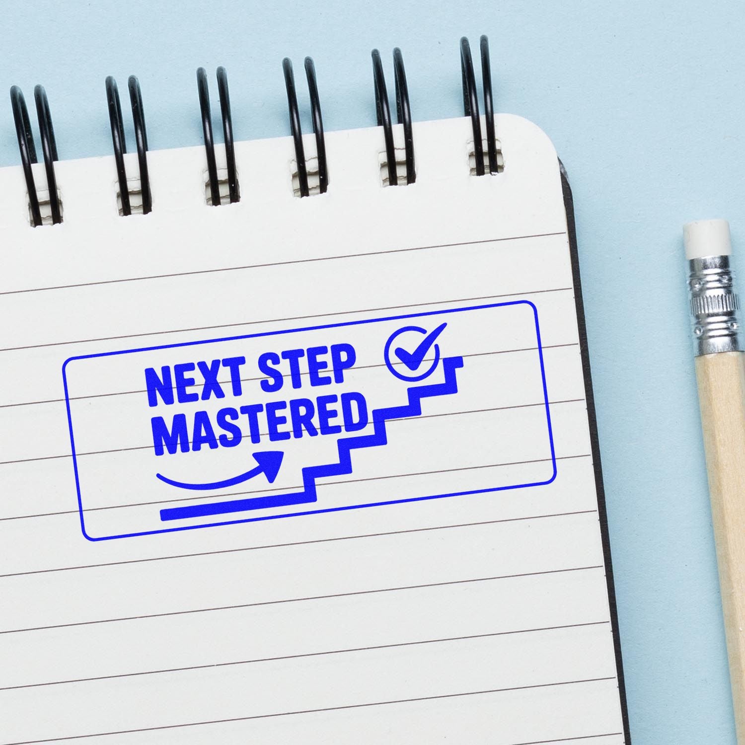 Blue rubber stamp reading Next Step Mastered on a notebook, perfect for tracking progress, achievements, and approvals.