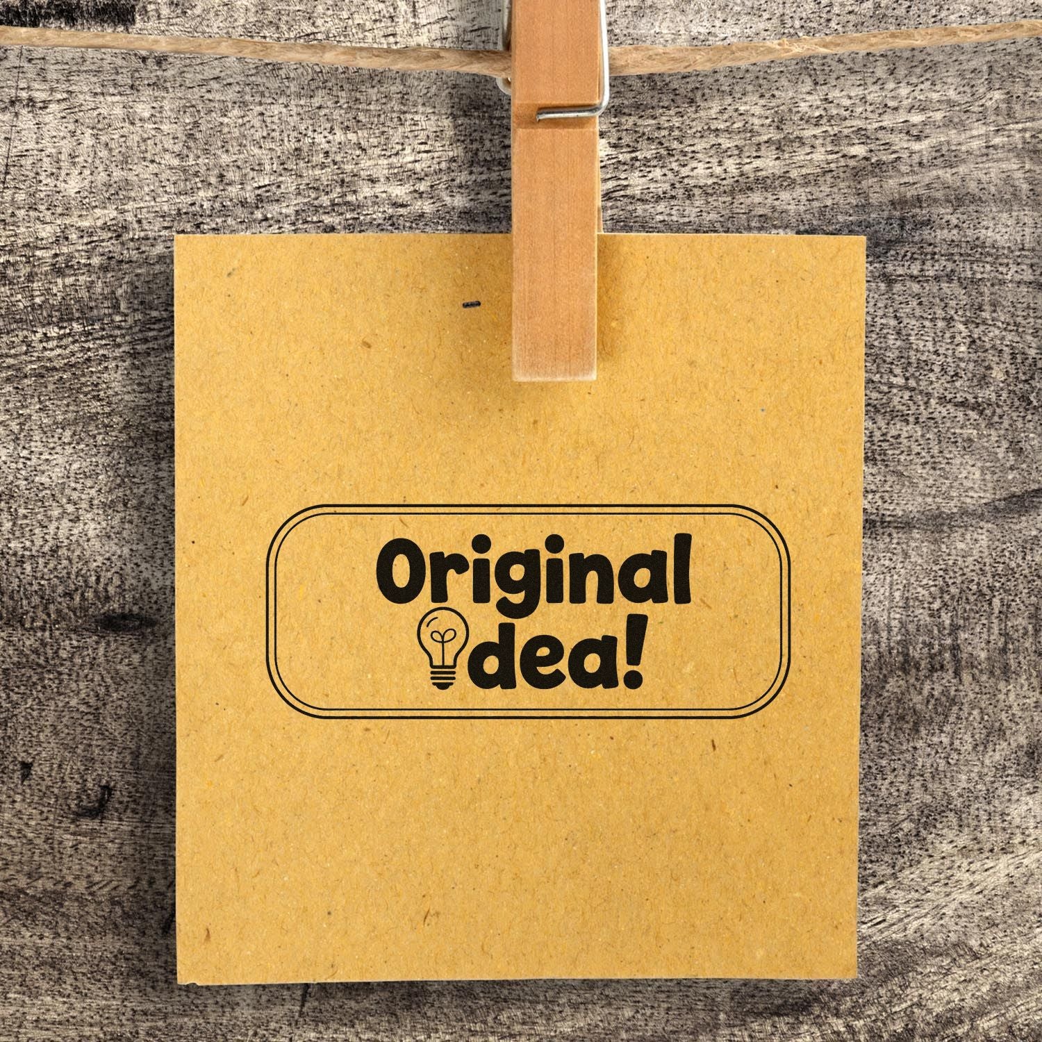 Original idea! custom rubber stamp on kraft paper with lightbulb icon, clipped to a rustic wood background.
