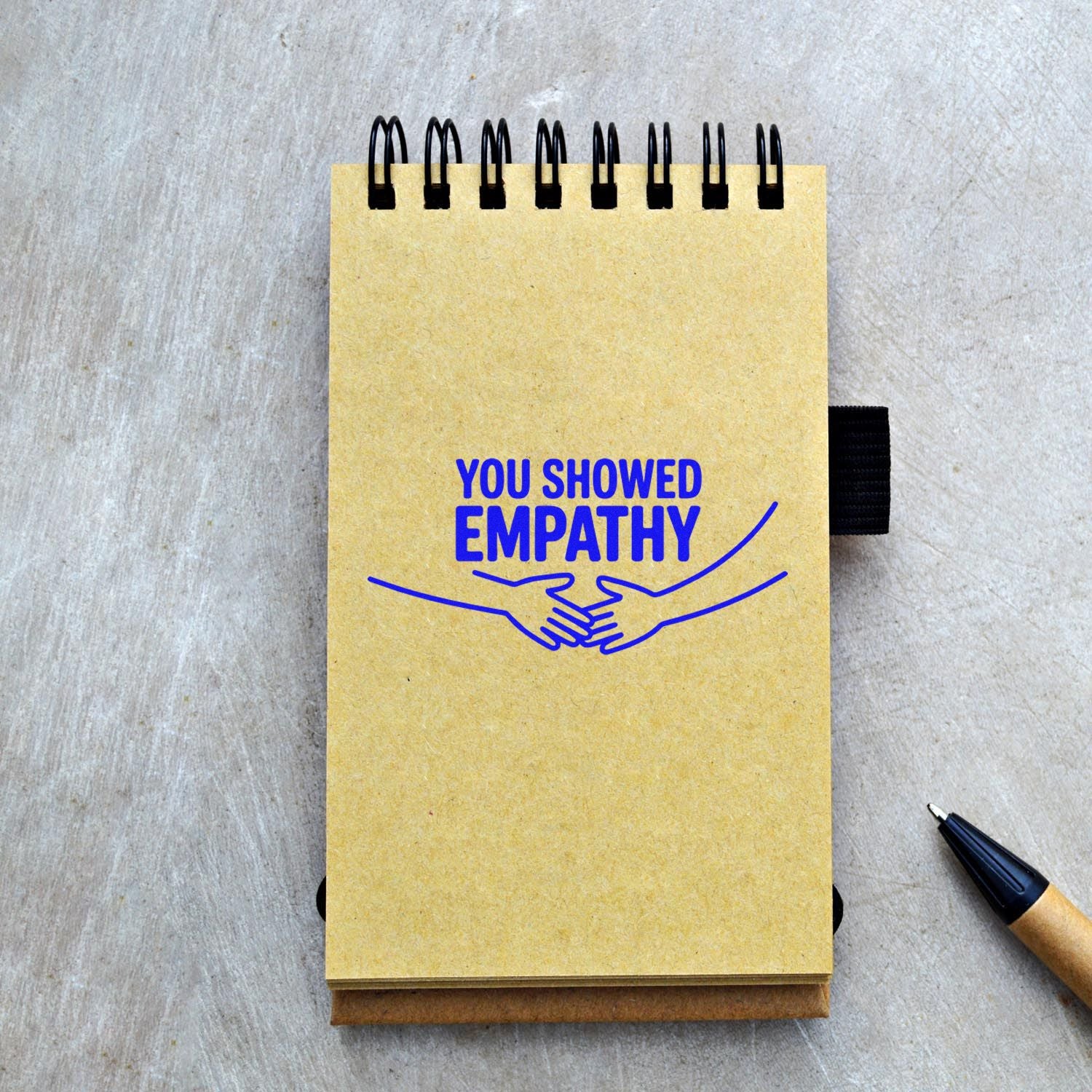 Rubber stamp impression reading You showed empathy with handshake design on a notebook for appreciation notes.