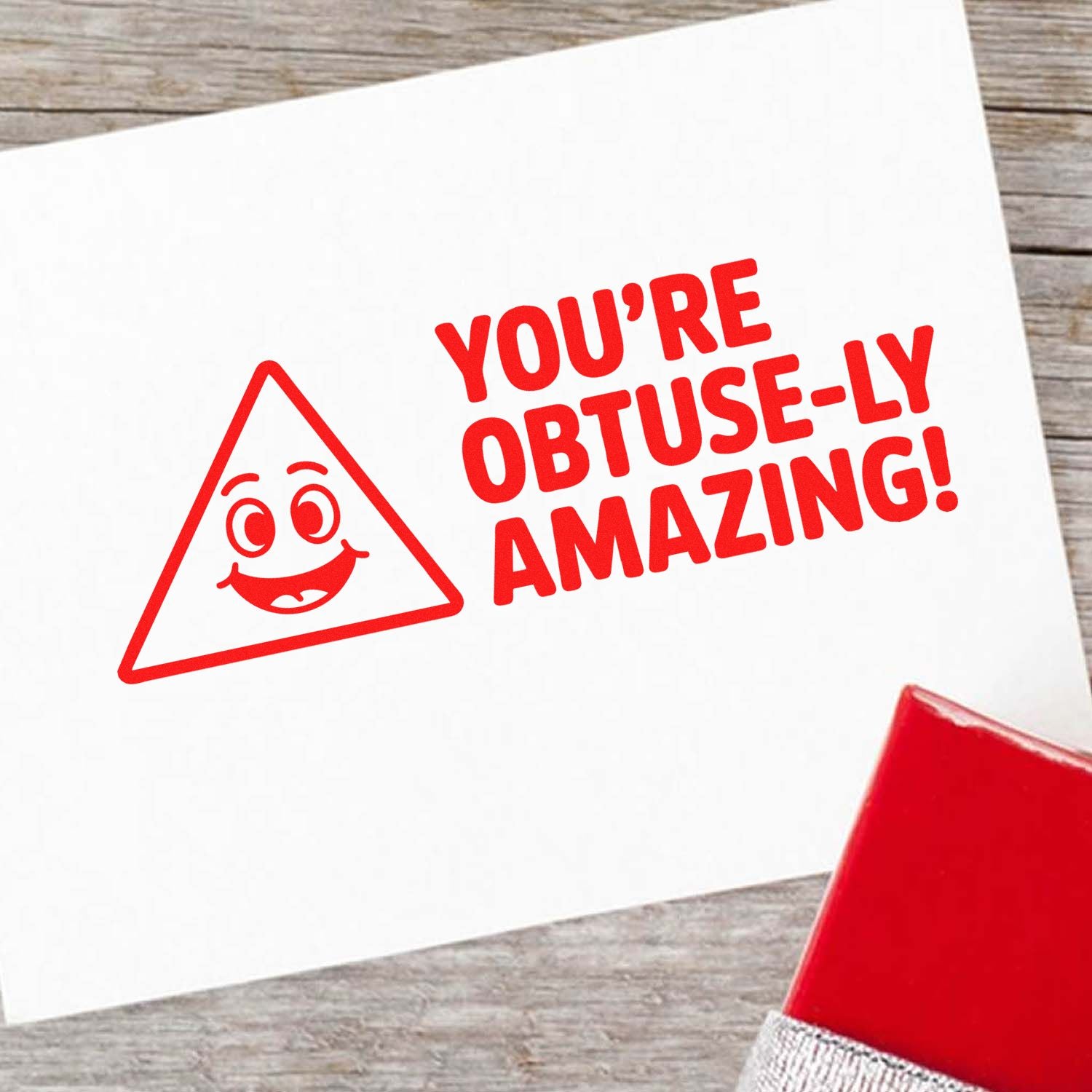 Custom rubber stamp design with Youre obtuse-ly amazing! text and smiling triangle icon on white paper.