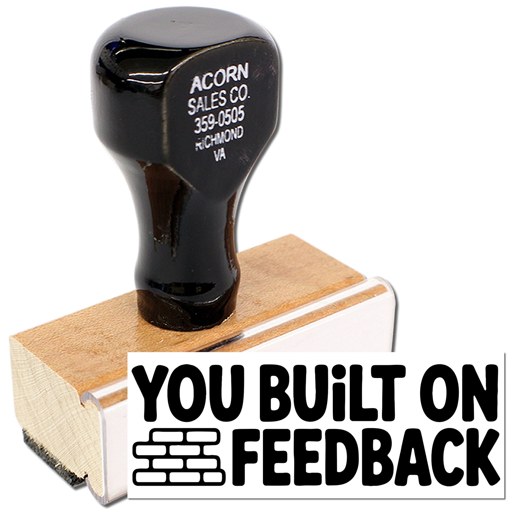 Wood-mounted custom rubber stamp reading You Built on Feedback with brick icon for business branding.