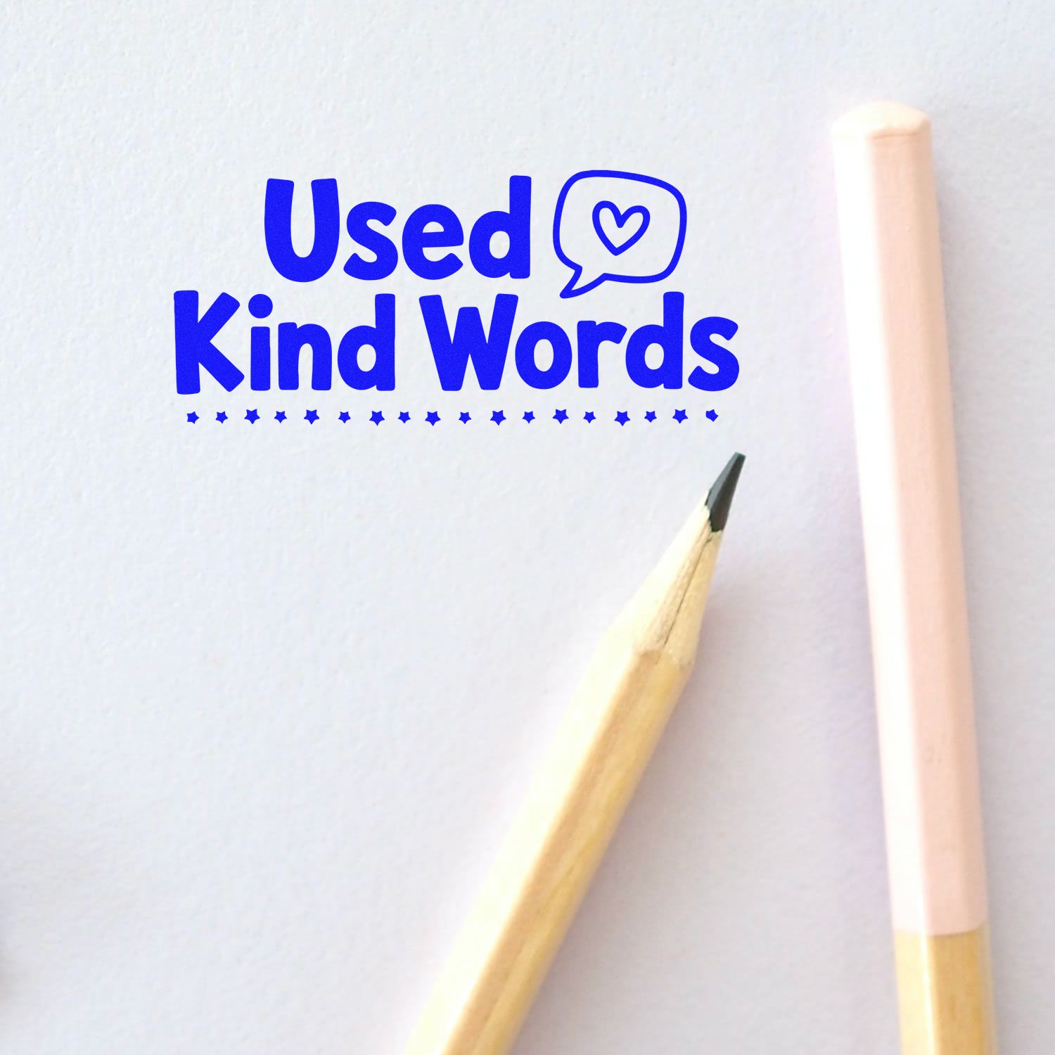 Used Kind Words rubber stamp design in blue with heart speech bubble, shown on paper with pencil for positive classroom or office use.