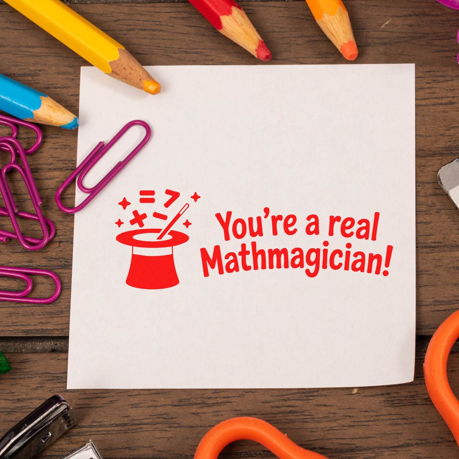 Red math teacher rubber stamp saying Youre a real Mathmagician! with magic hat icon on white paper.