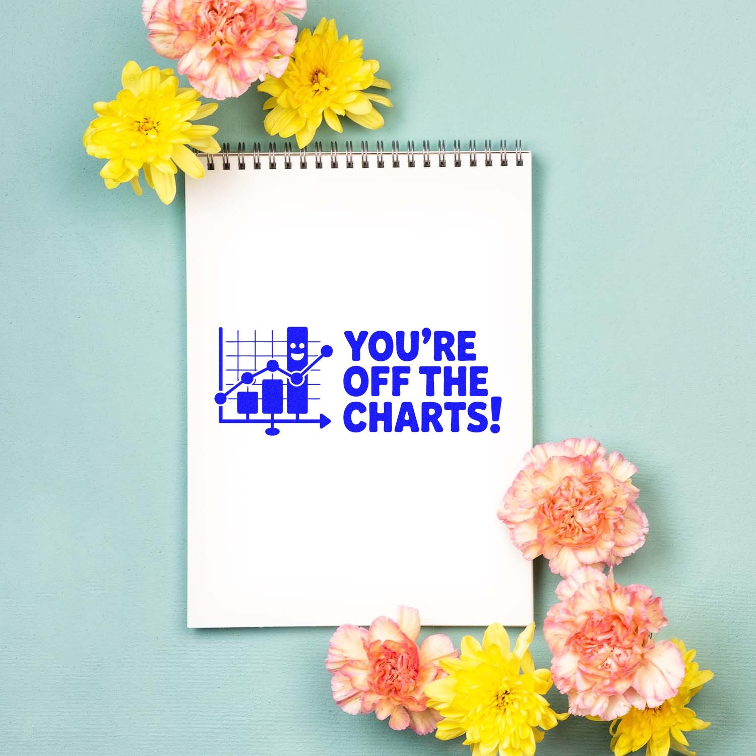 Rubber stamp design reading Youre Off the Charts! with chart icon on notebook page