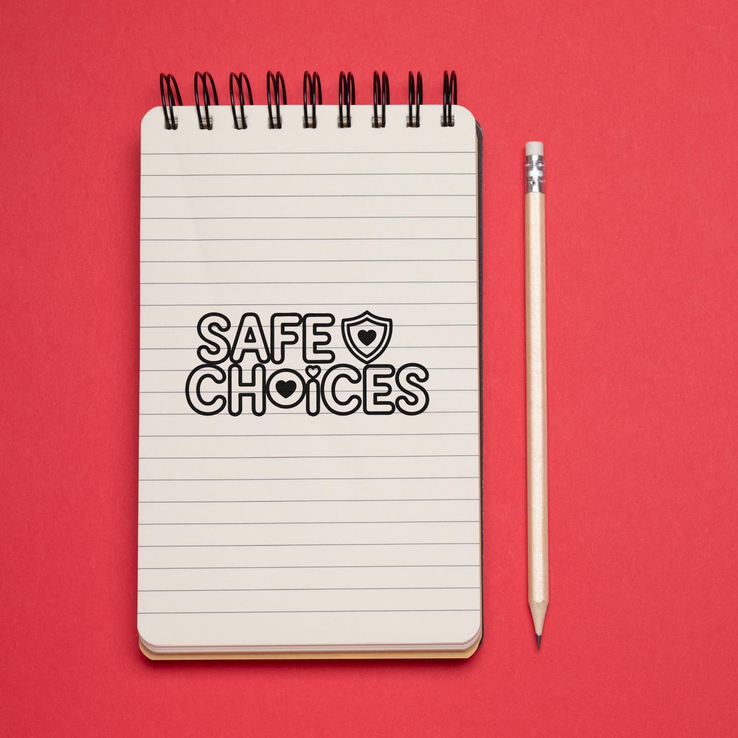 Safe Choices rubber stamp impression on a lined notebook with pencil on a red background.