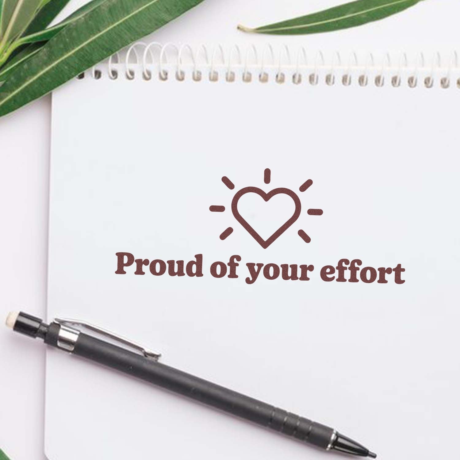 Proud of Your Effort rubber stamp with heart icon on notebook, ideal for teacher feedback and encouragement.