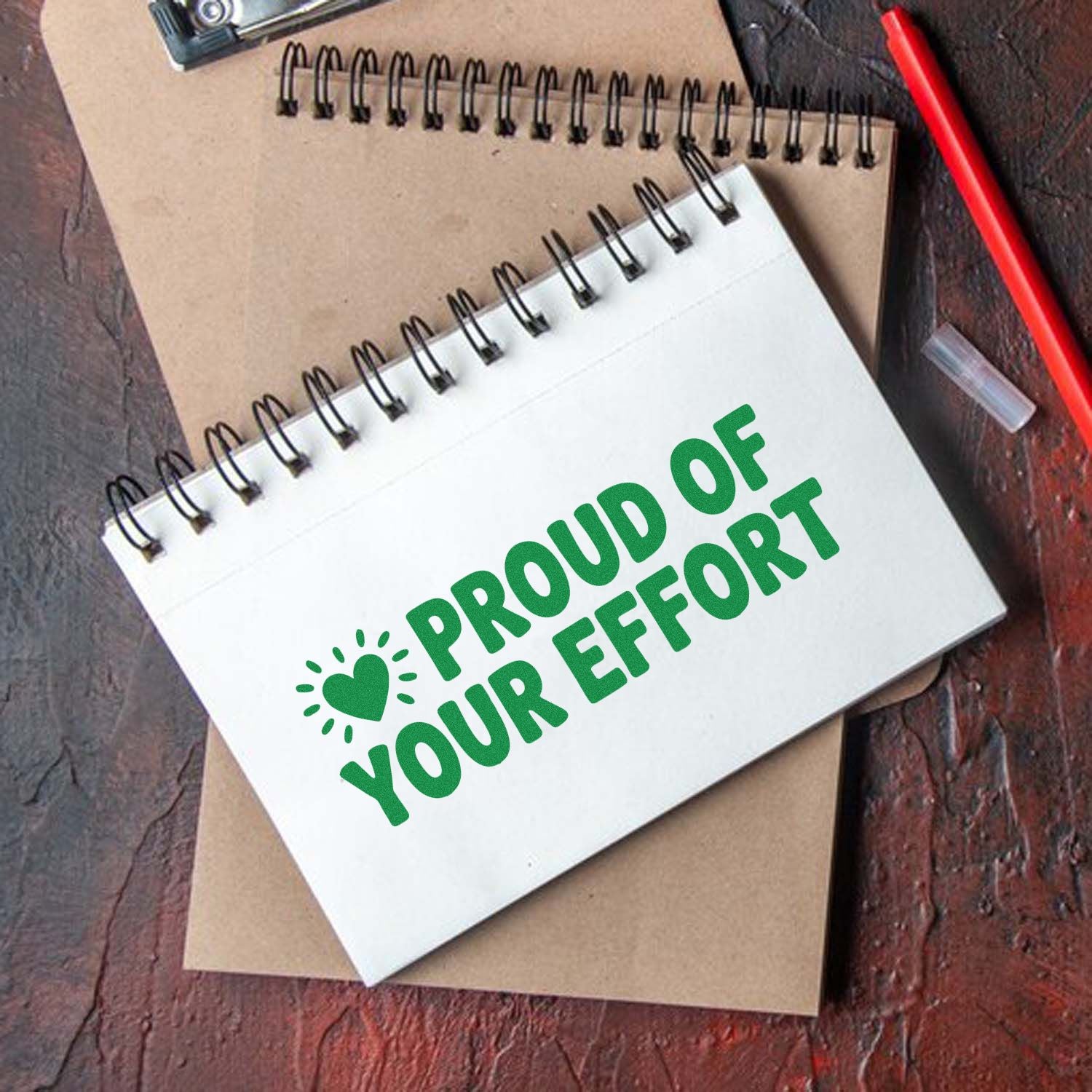 Green motivational rubber stamp reading Proud of Your Effort on a spiral notebook, perfect for teacher awards.