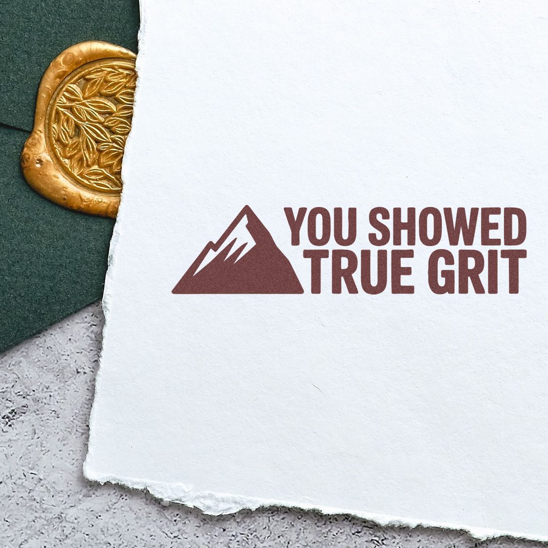 Custom rubber stamp impression with mountain logo and You showed true grit motivational message on paper