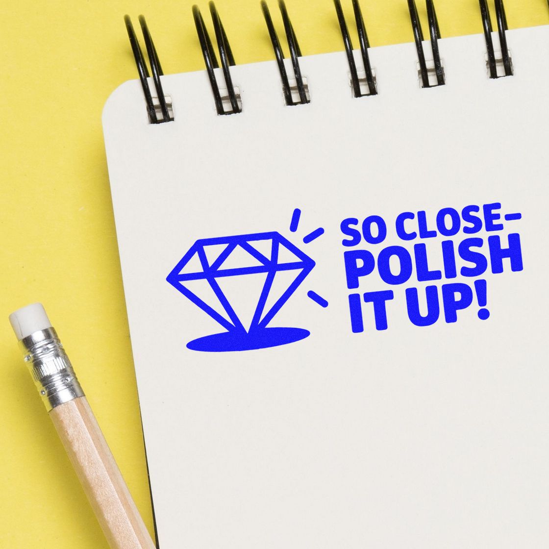 Custom rubber stamp design reading So ClosePolish It Up! with diamond icon on notebook for creative branding.