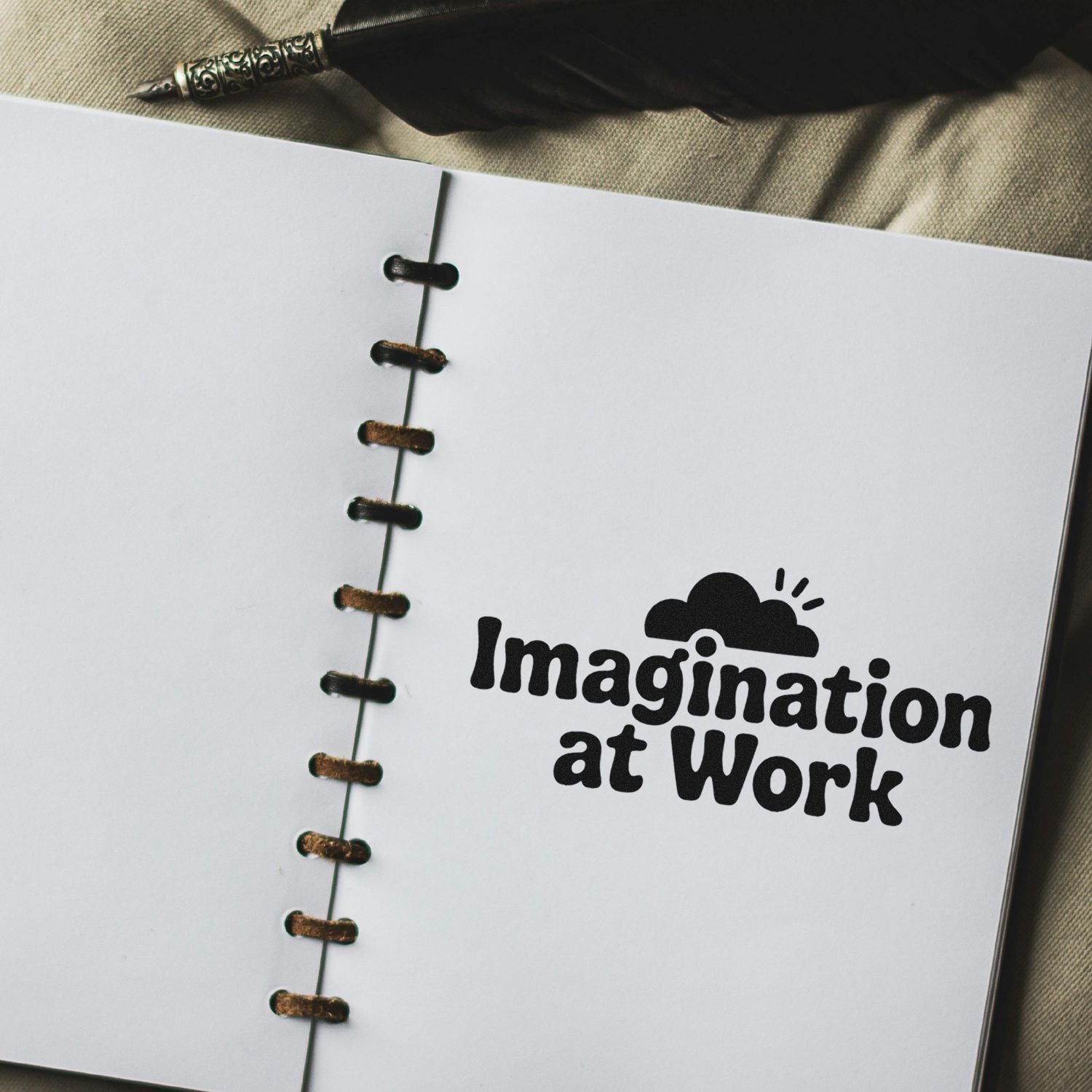 Custom rubber stamp reading Imagination at Work on a notebook page with pen, ideal for creative branding and stationery use.