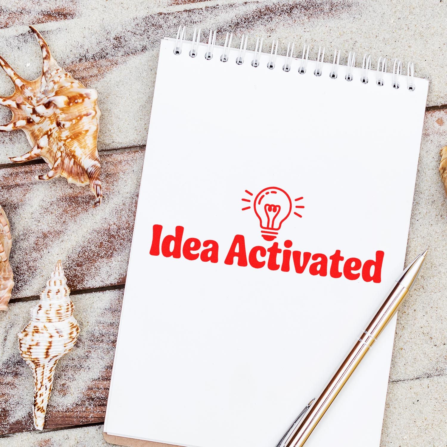 Red Idea Activated rubber stamp impression on notebook with lightbulb icon, ideal for creative business branding and office use.