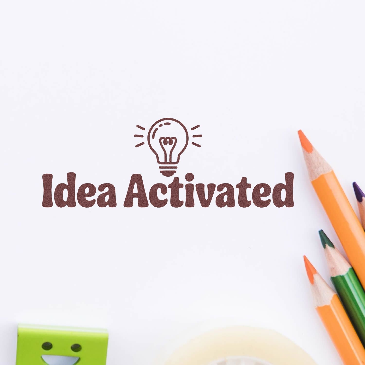 Idea Activated rubber stamp with lightbulb icon and colored pencils for creative brainstorming and office stationery.