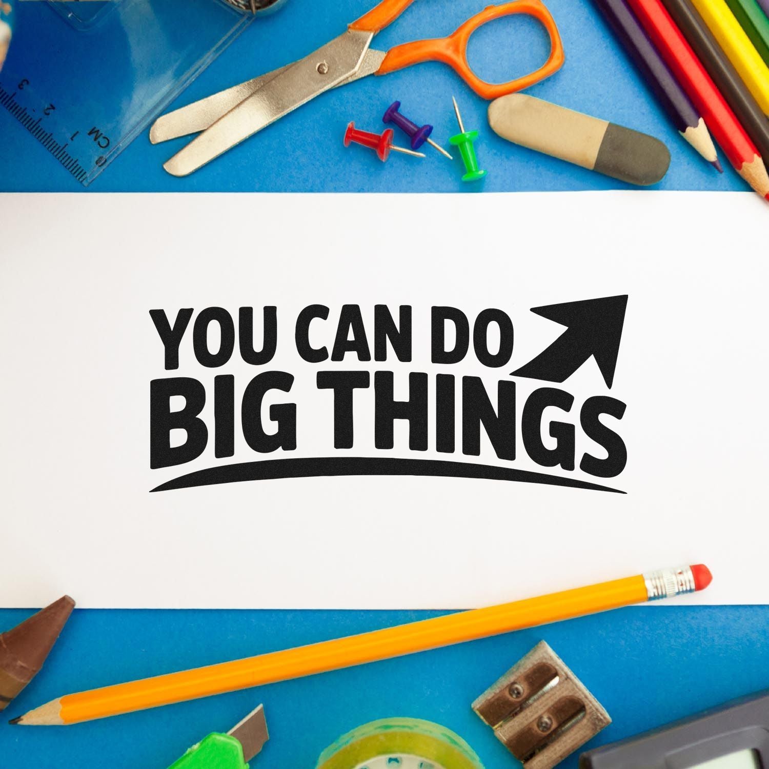 Motivational rubber stamp design reading You Can Do Big Things with school supplies on a blue desk background.