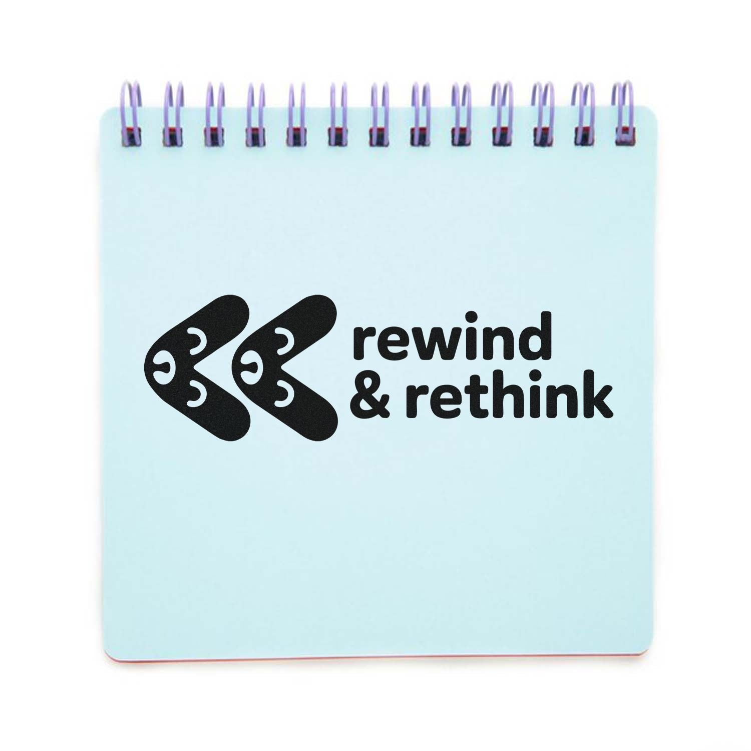Custom rubber stamp design with rewind & rethink text and rewind icon on a spiral notebook.