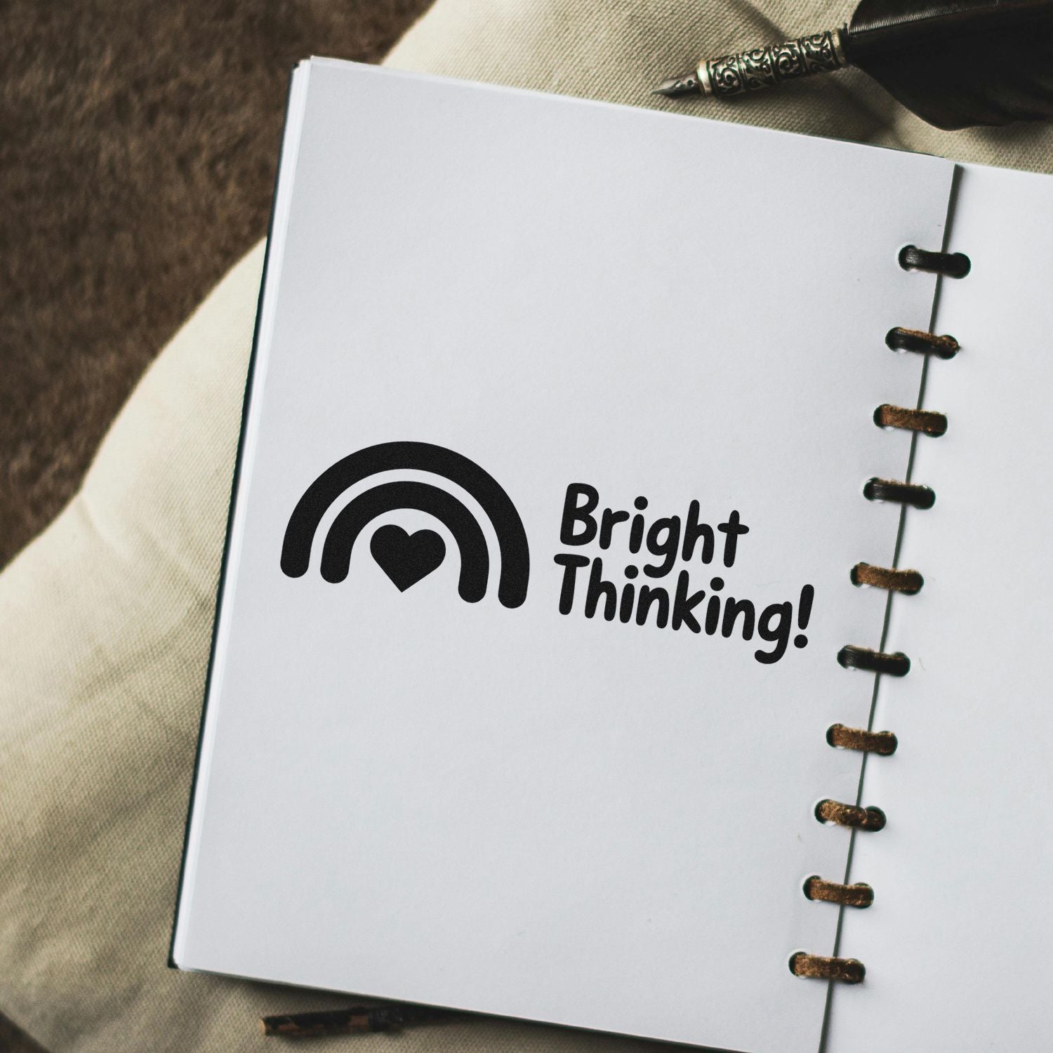 Custom rubber stamp with rainbow heart and Bright Thinking! logo stamped on a notebook page.