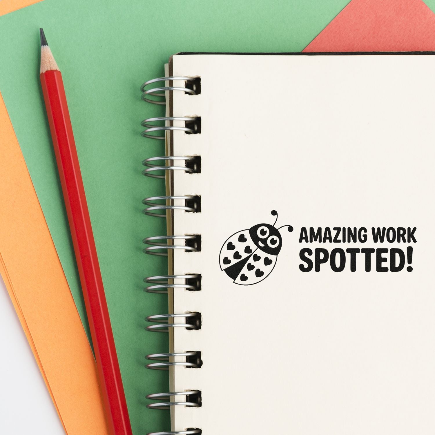 Ladybug rubber stamp reading Amazing Work Spotted! on a notebook, perfect for teacher reward and office praise.