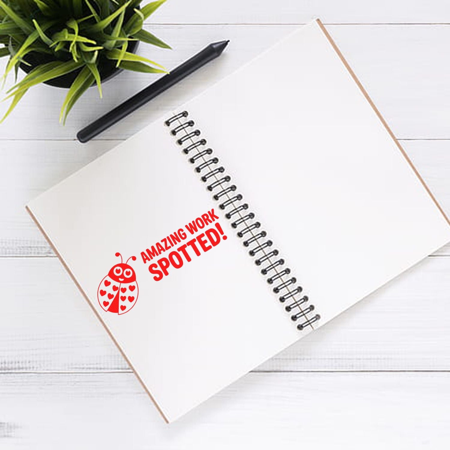 Red Amazing Work Spotted! rubber stamp with ladybug on a notebook, ideal for classroom or office praise.