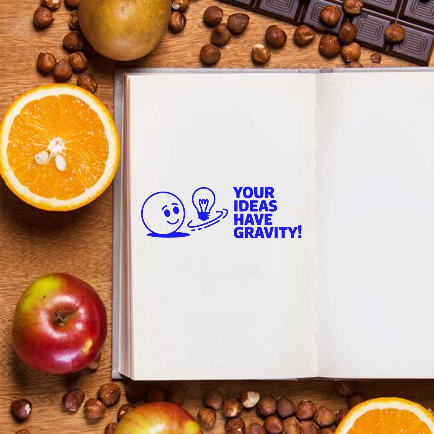Custom rubber stamp with Your Ideas Have Gravity! on open notebook, featuring lightbulb design and inspirational quote.