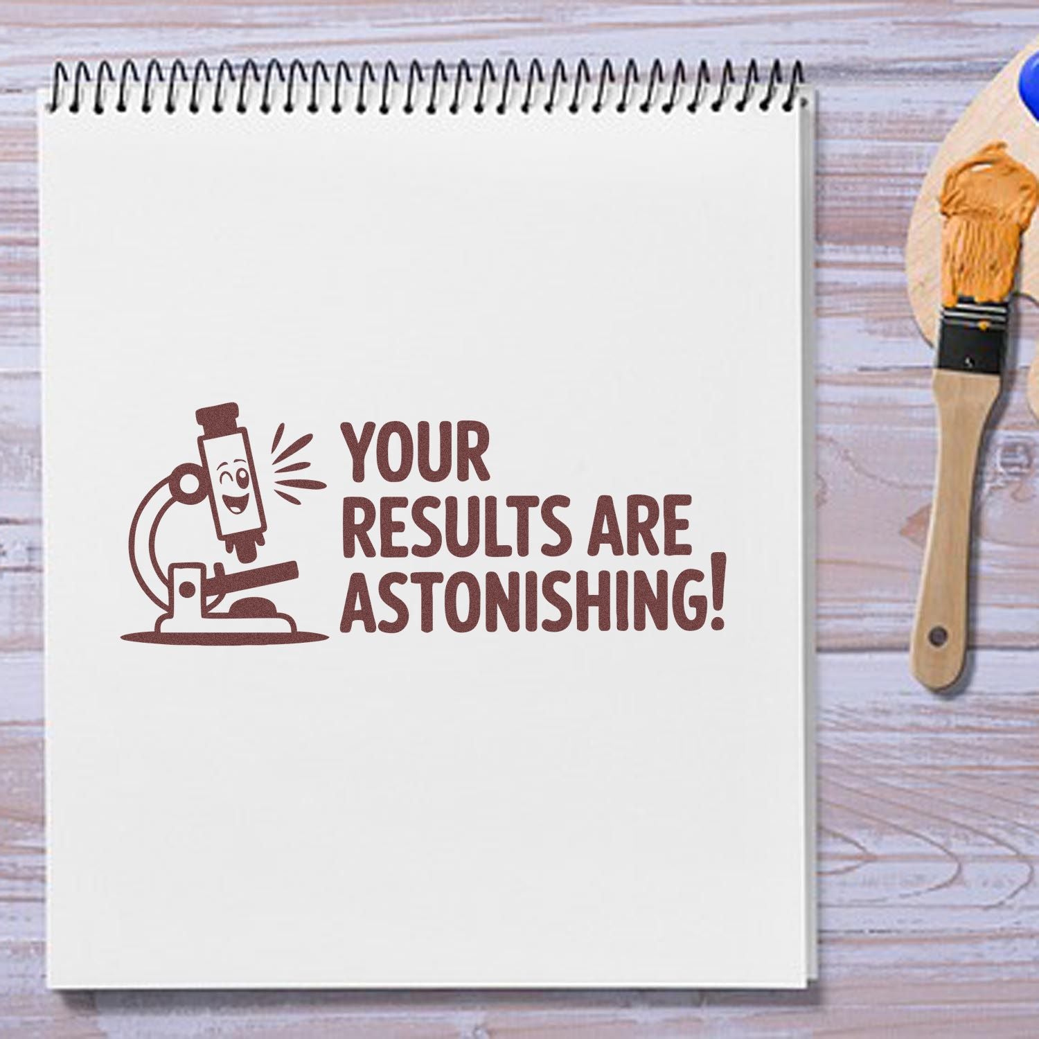Rubber stamp impression on notebook reading Your Results Are Astonishing! with microscope design for crafting and stationery.