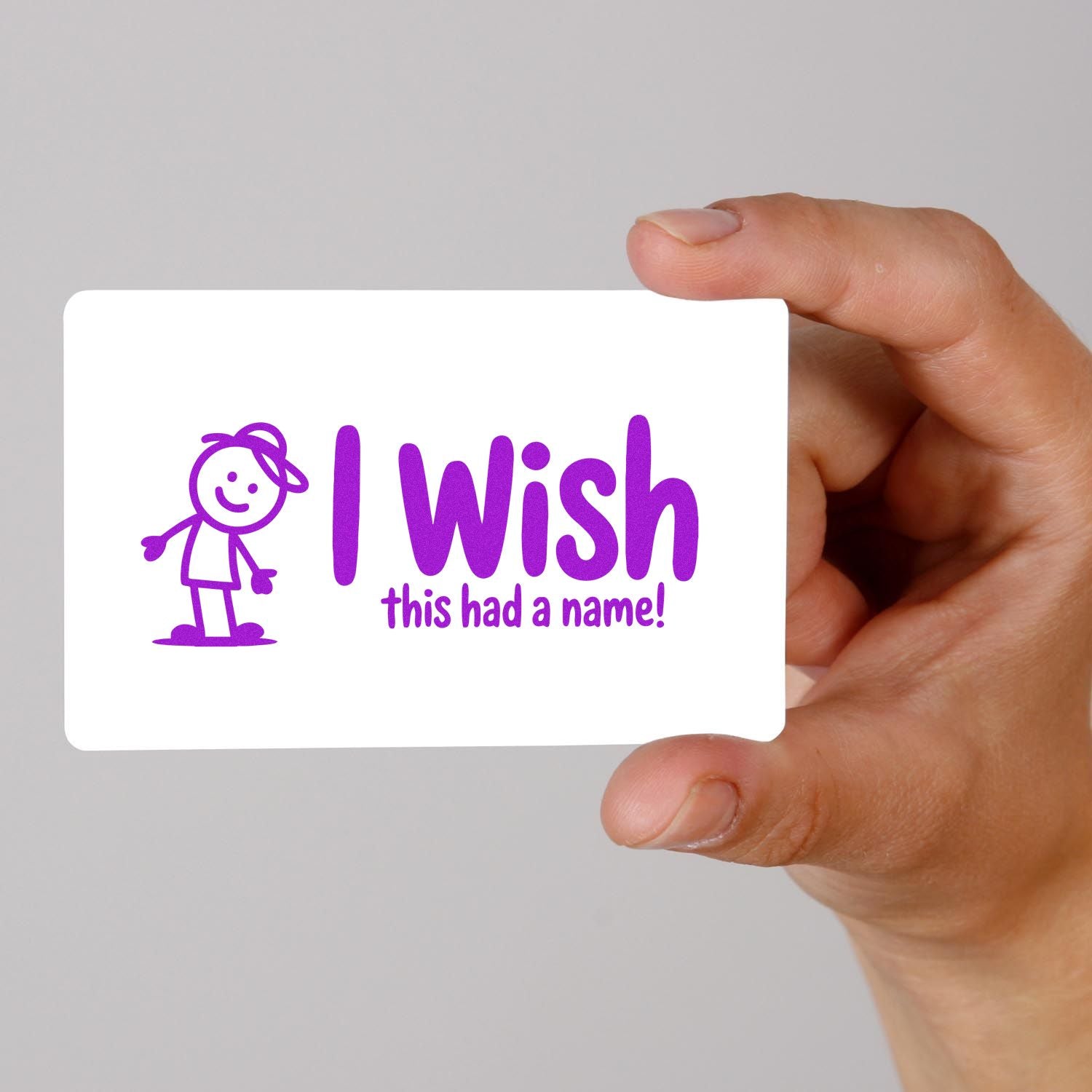 Hand holding a custom rubber stamp sample with purple I wish this had a name! design and cartoon figure.