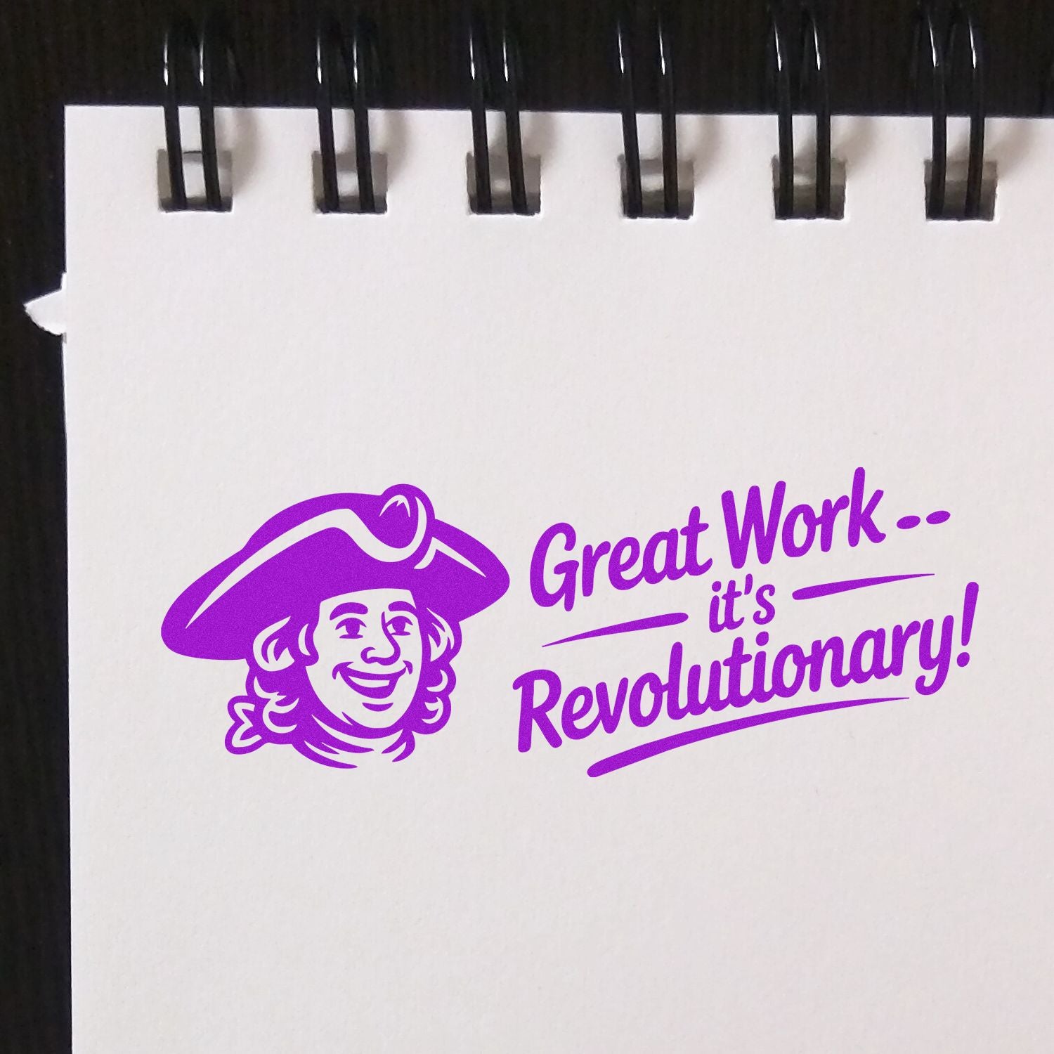 Custom rubber stamp imprint in purple reads Great Workits Revolutionary! with a revolutionary portrait on notebook paper.