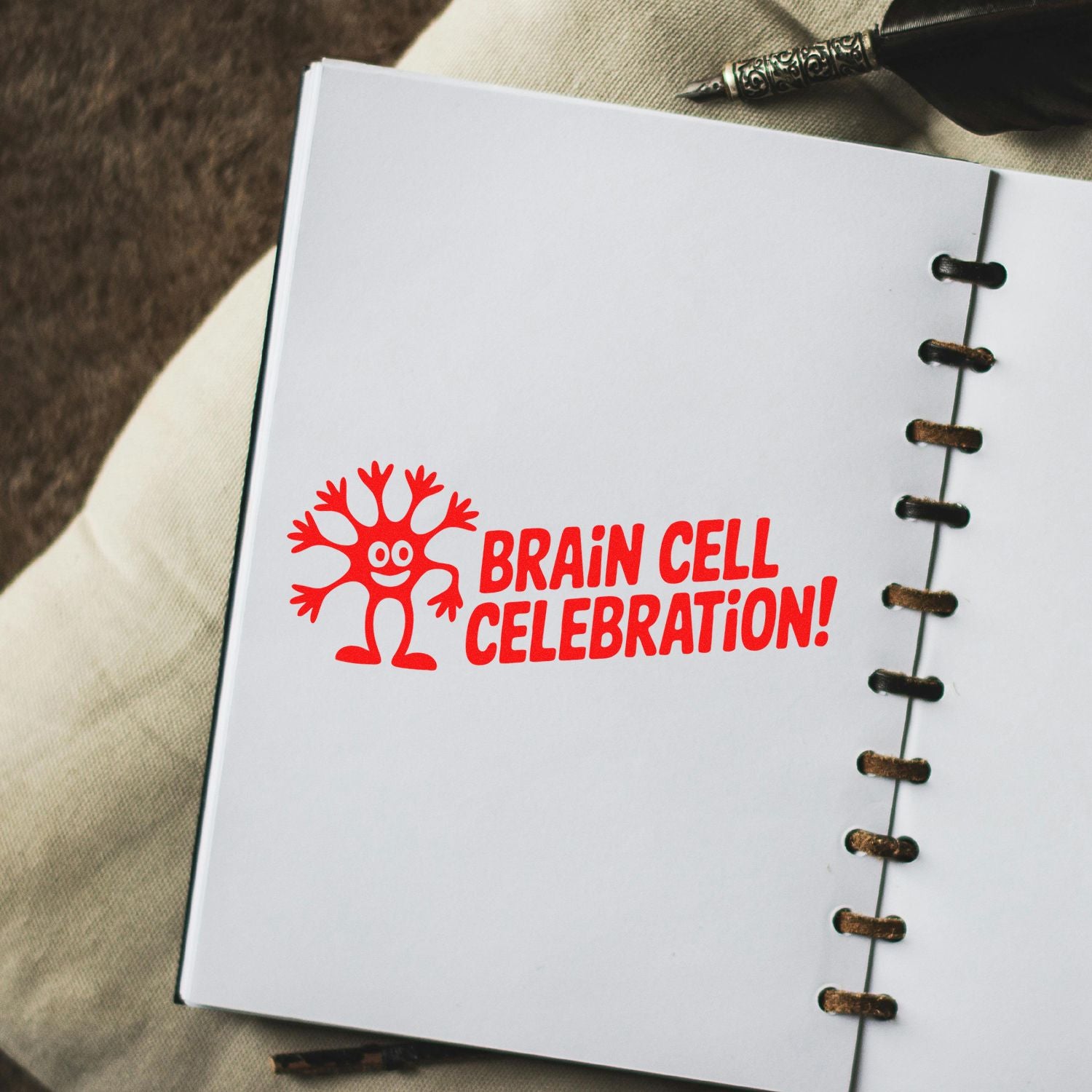 Red Brain Cell Celebration rubber stamp impression on a notebook page, a playful custom stamp for office or classroom stationery.