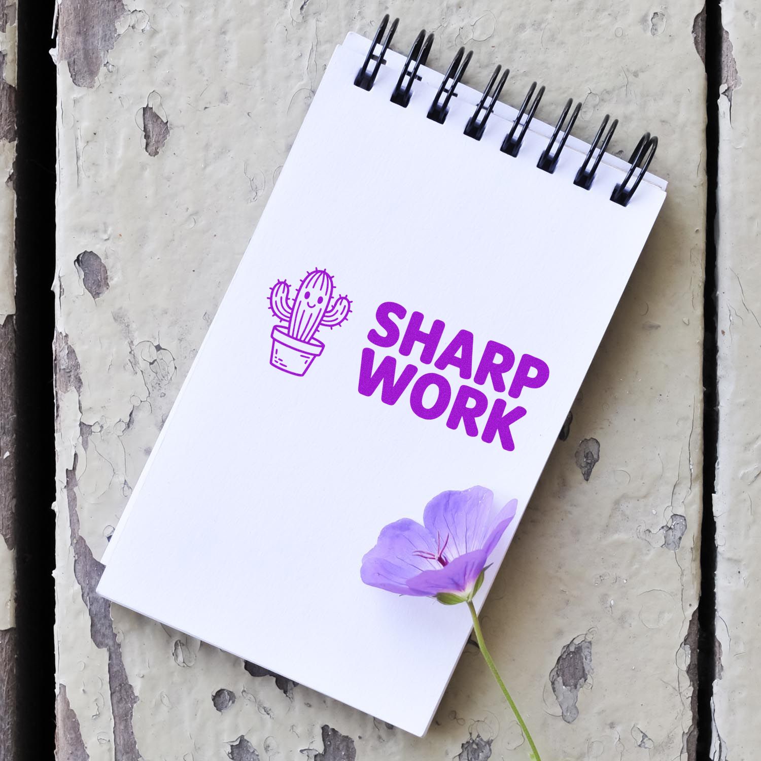 Custom rubber stamp mockup with cactus icon and Sharp Work logo on a spiral notebook.