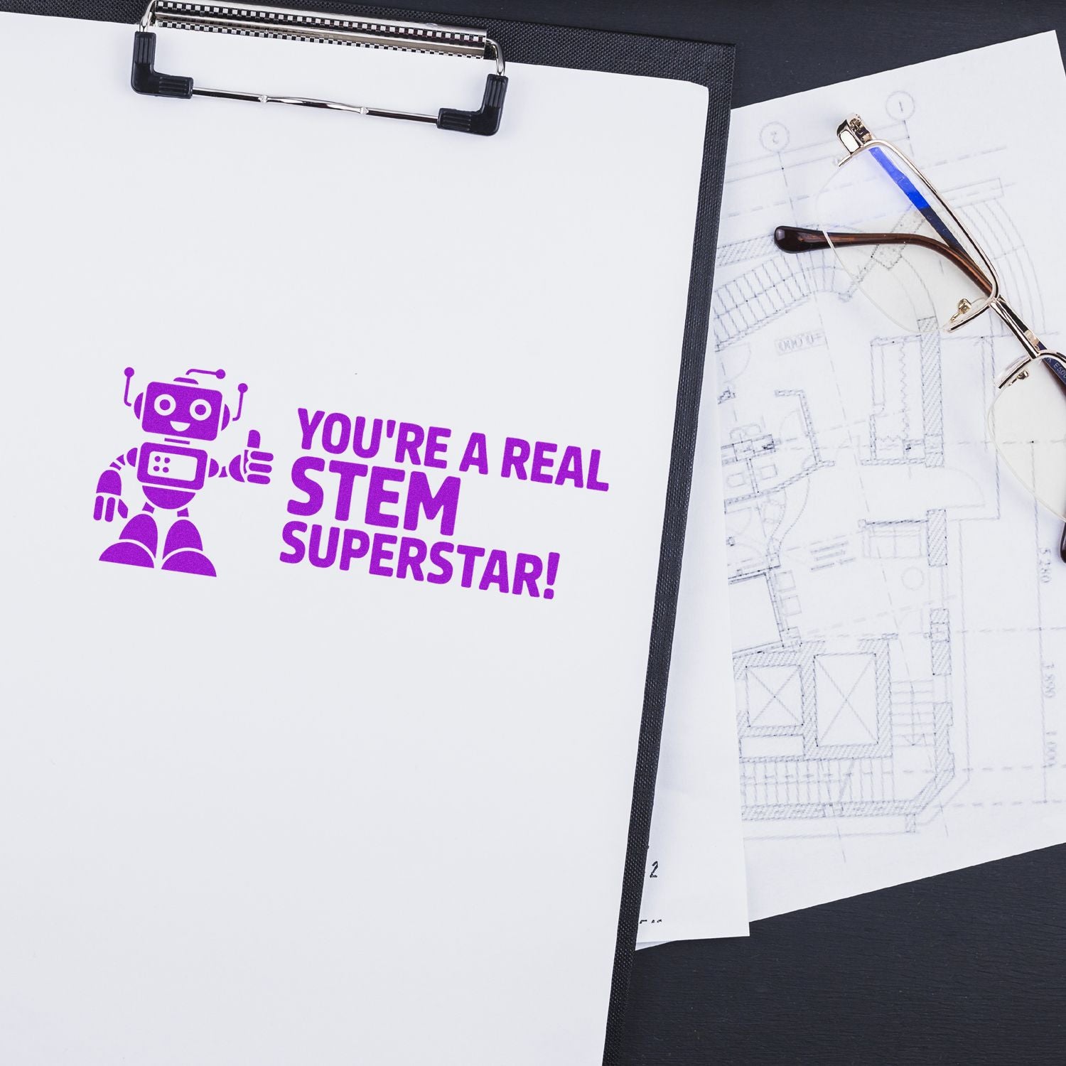 Purple custom rubber stamp impression reading Youre a real STEM superstar! with robot icon on clipboard and sketches.