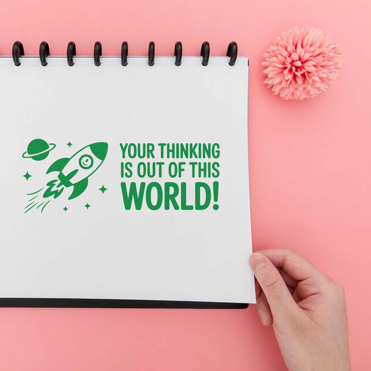 Space-themed rubber stamp with rocket and Your thinking is out of this world! on a notebook page.