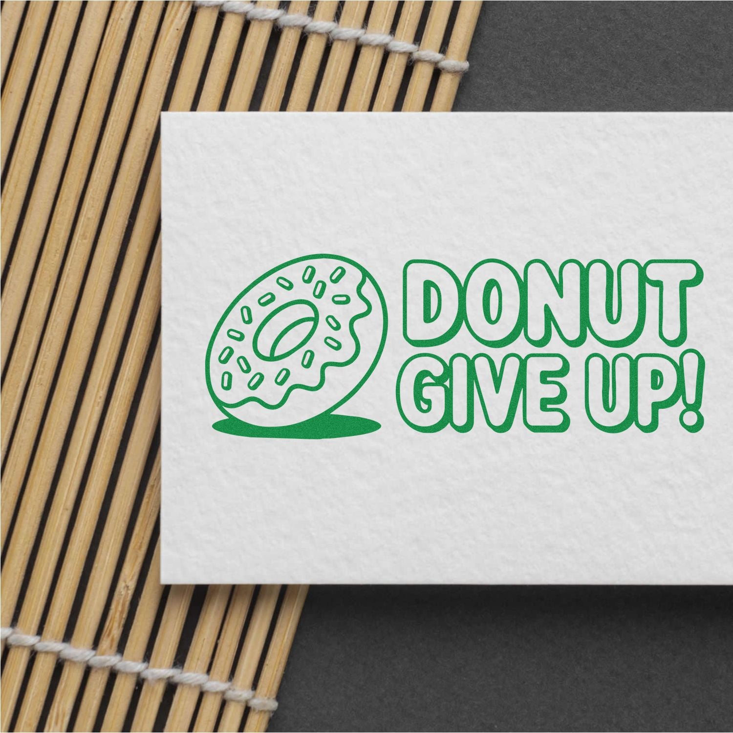 Custom rubber stamp design with donut illustration and Donut Give Up! motivational text on white paper.