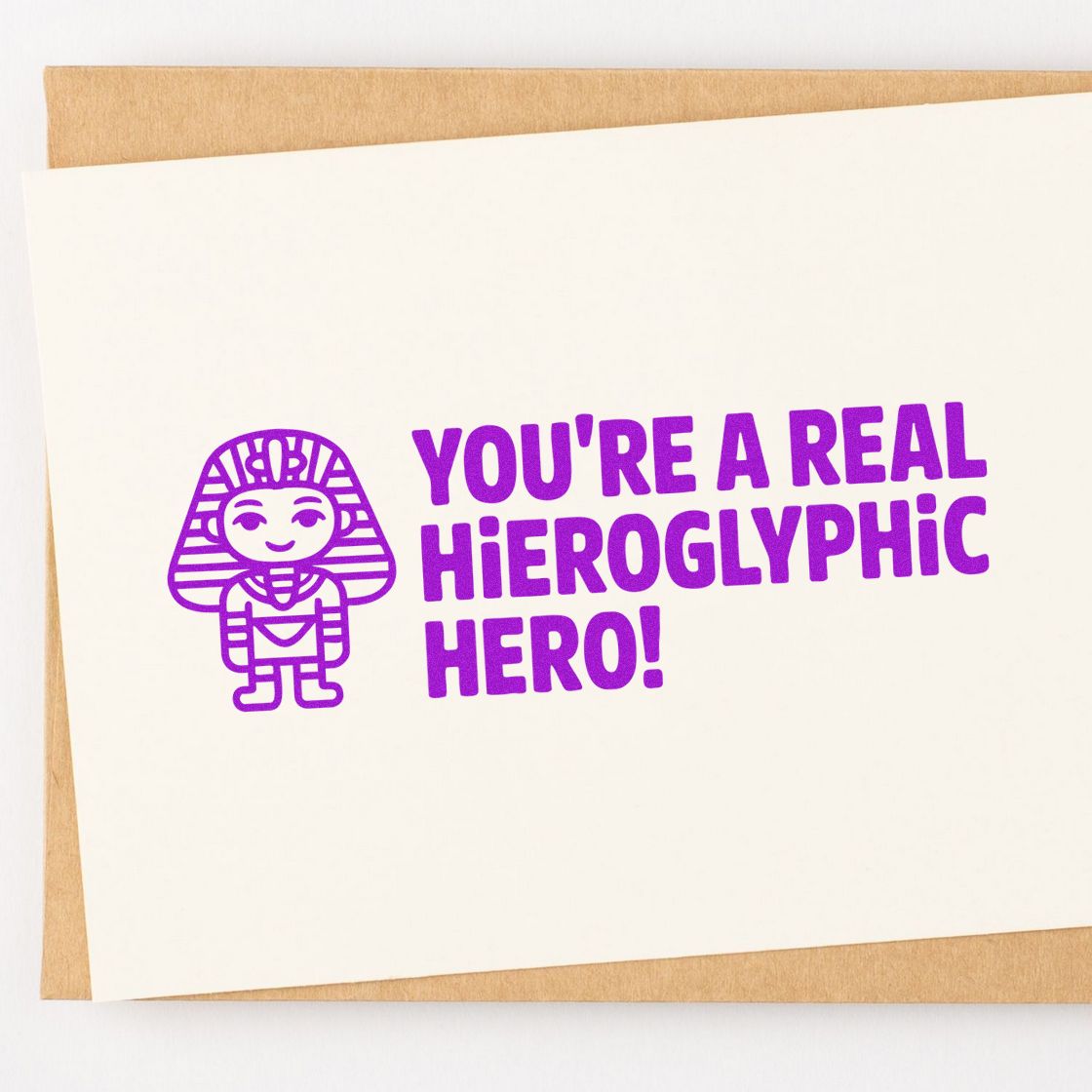 Purple rubber stamp imprint reading Youre a Real Hieroglyphic Hero! with pharaoh icon on white paper.